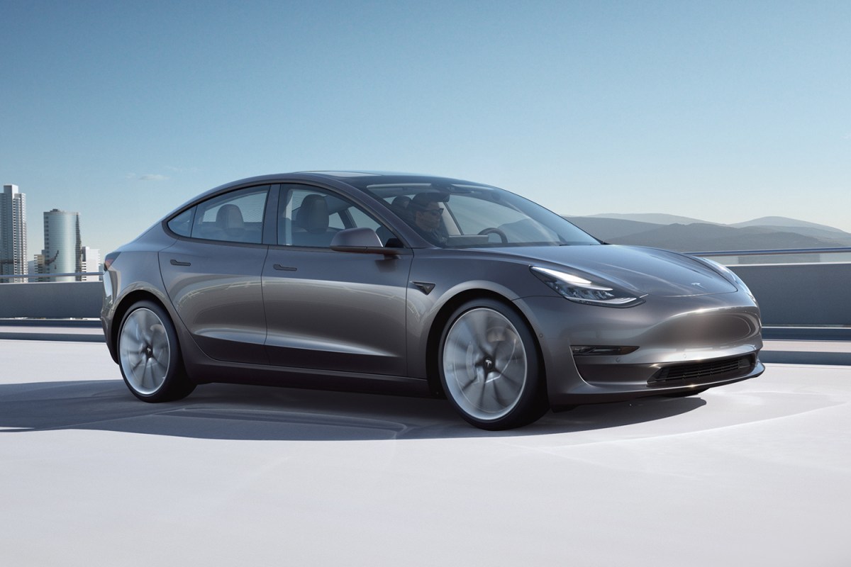 A silver Tesla Model 3 driving down the road. The electric car was just ranked first in the American-Made Index.