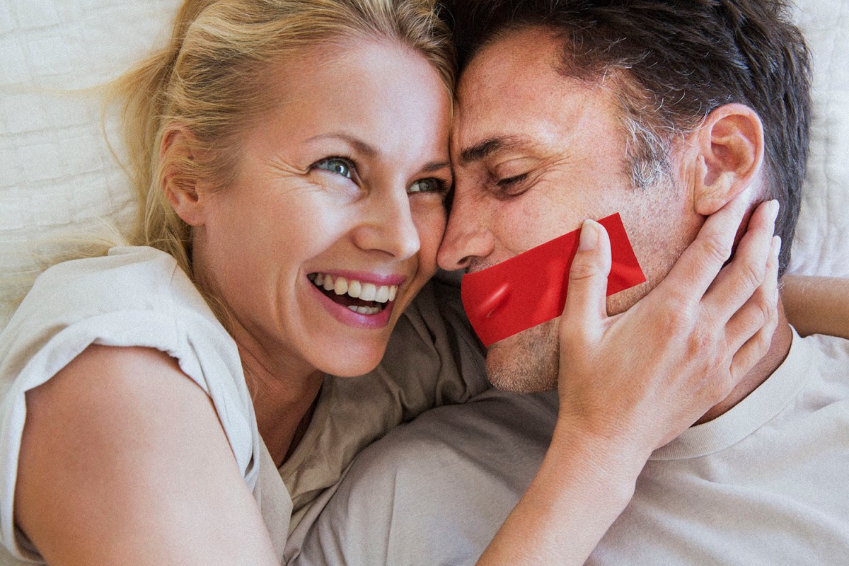 Couple in romantic embrace, woman laughing, man has tape over his mouth