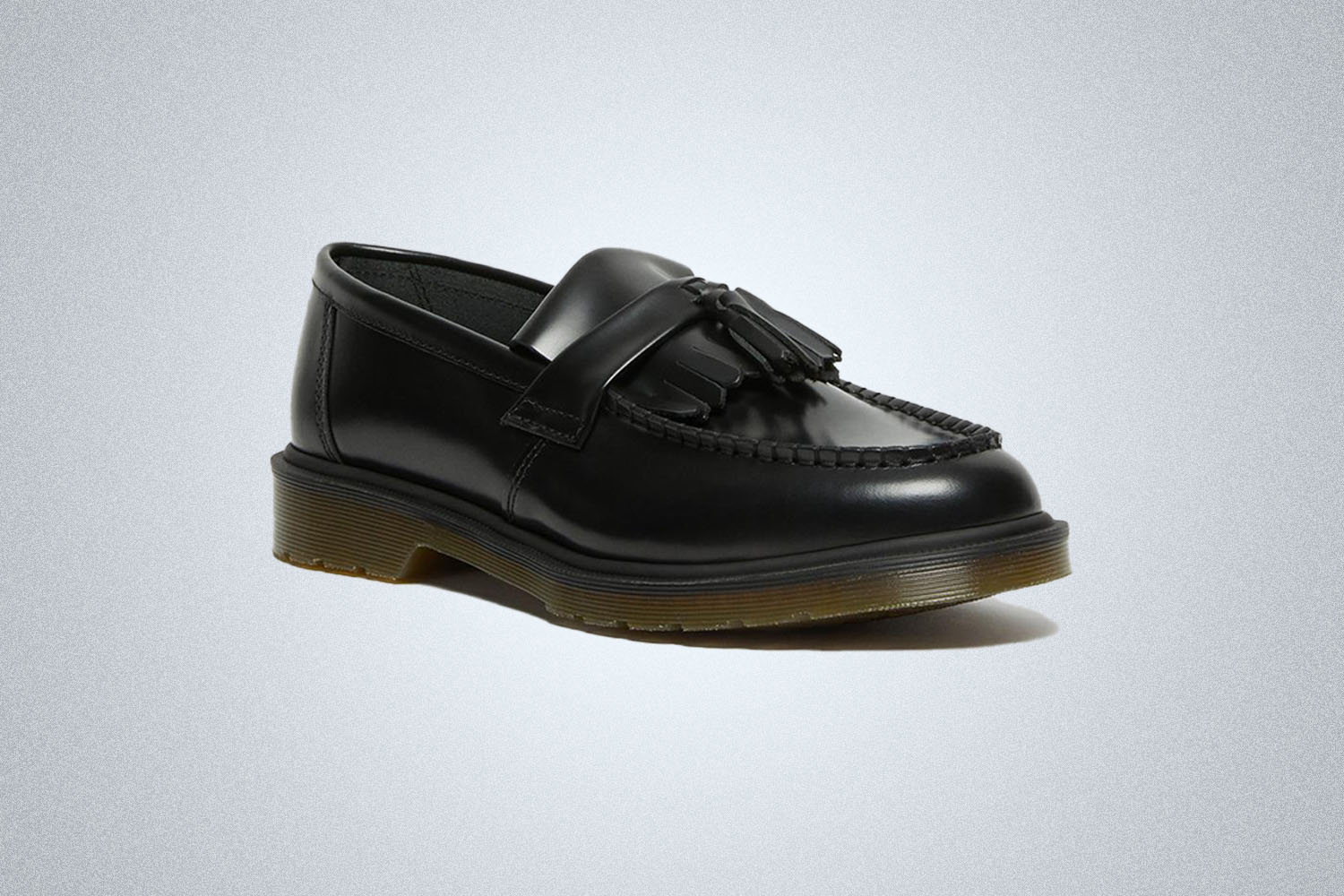 A pair of black leather loafers from Doc Martens on a grey background