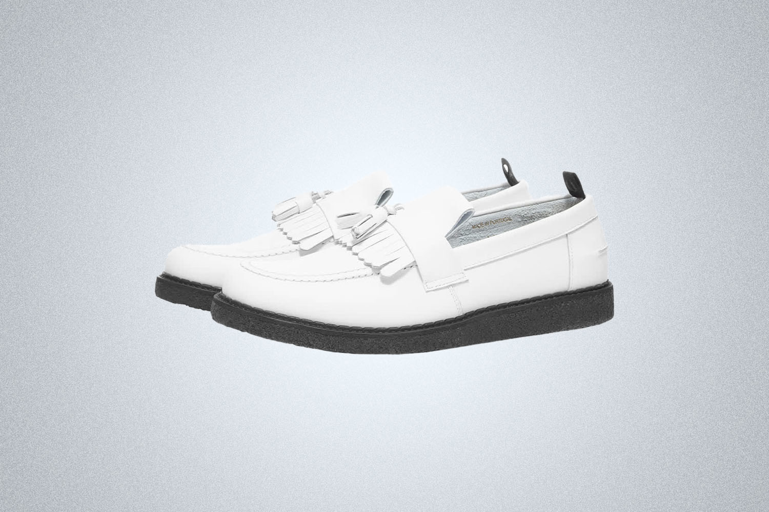a tasseled white loafer from Fred Perry on a grey background