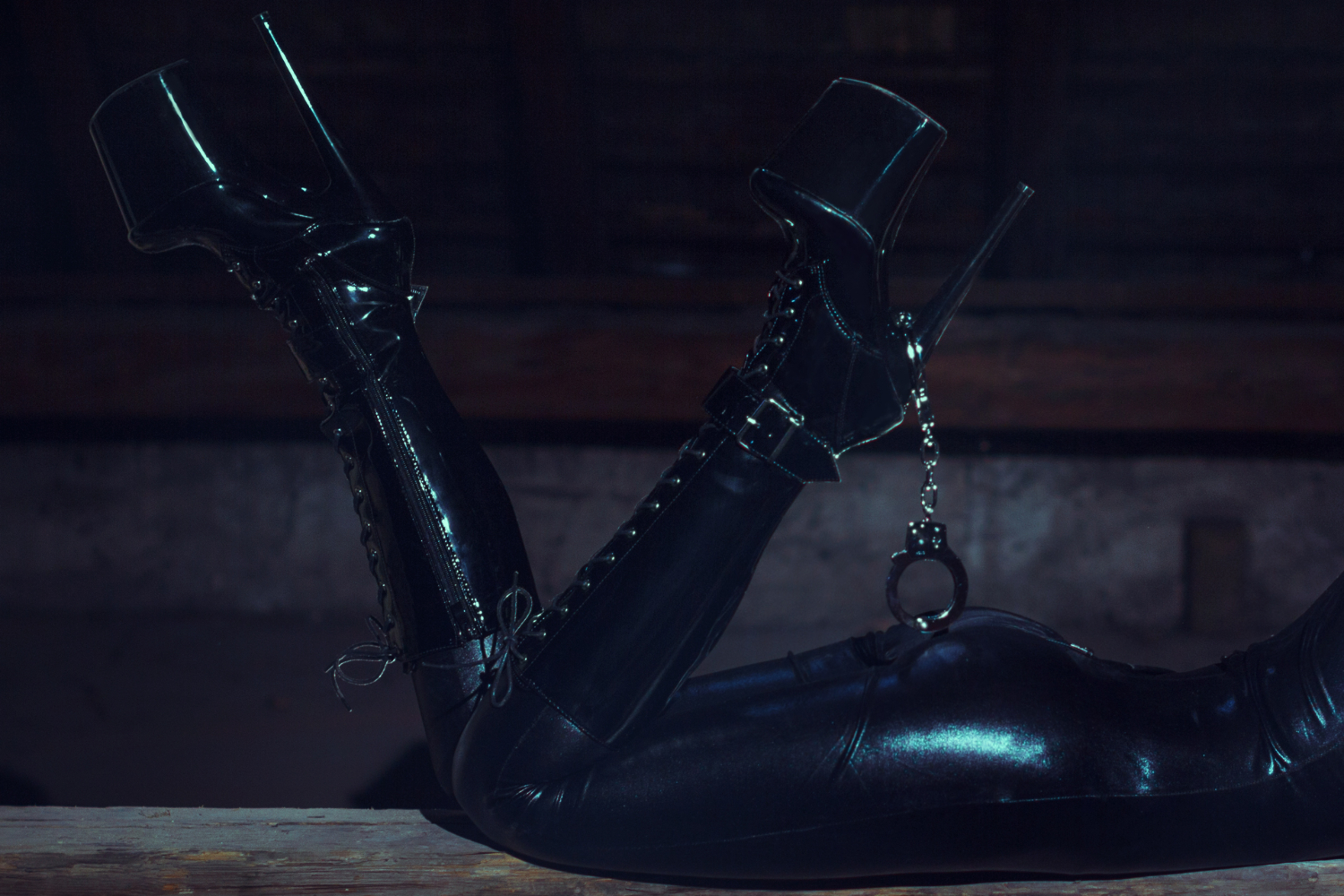 Woman's legs wearing black leather pants and platform boots with handcuffs dangling from heel