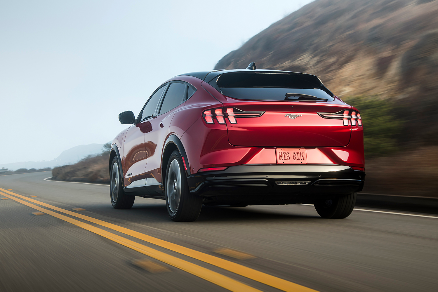 The rear end of a red Ford Mustang Mach-E driving down the road. Here's our review of the electric crossover.