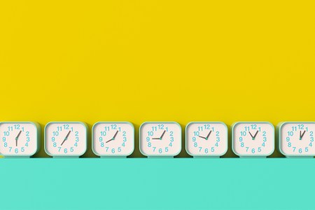 A series of seven clocks with different times lined up against a yellow and teal background