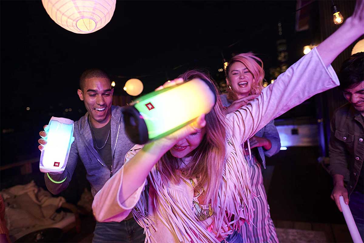 Three people dancing and showing off the LED light show built into the JBL Pulse 4 speaker