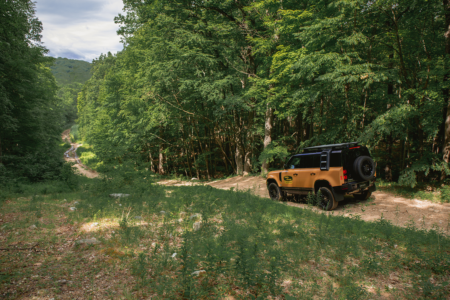 A Land Rover Defender Trophy Edition facing down an off-road trail, like one at the company's Biltmore Driving Center