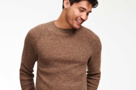 A man wearing a marled brown Cashmere Waffle Crewneck Sweater from Naadam, now 50% off