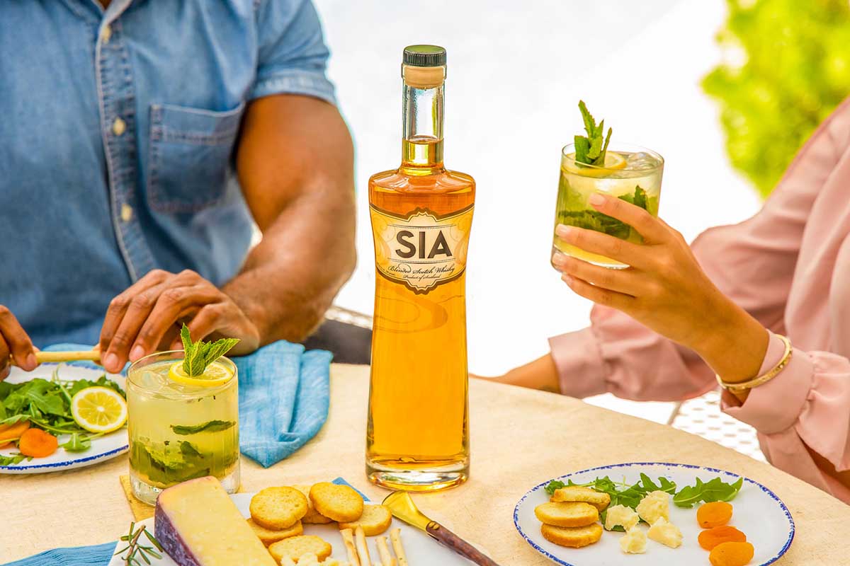 Two people at a dinner table sipping cocktails made from a bottle of SIA Scotch Whisky