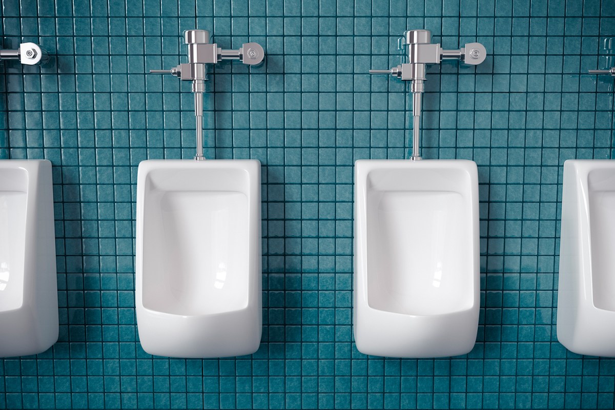 White urinals on a blue tiled wall in a bathroom