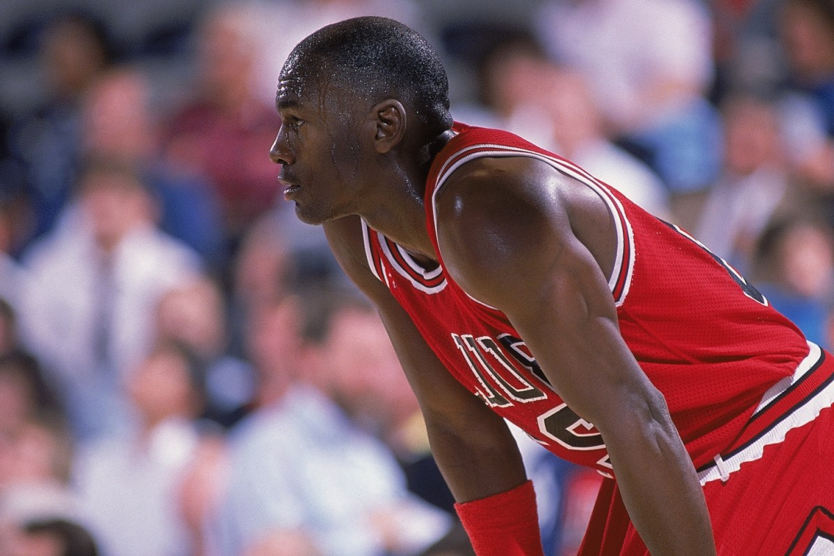 Michael Jordan #23 of the Chicago Bulls rests on the court during a game in red uniform.