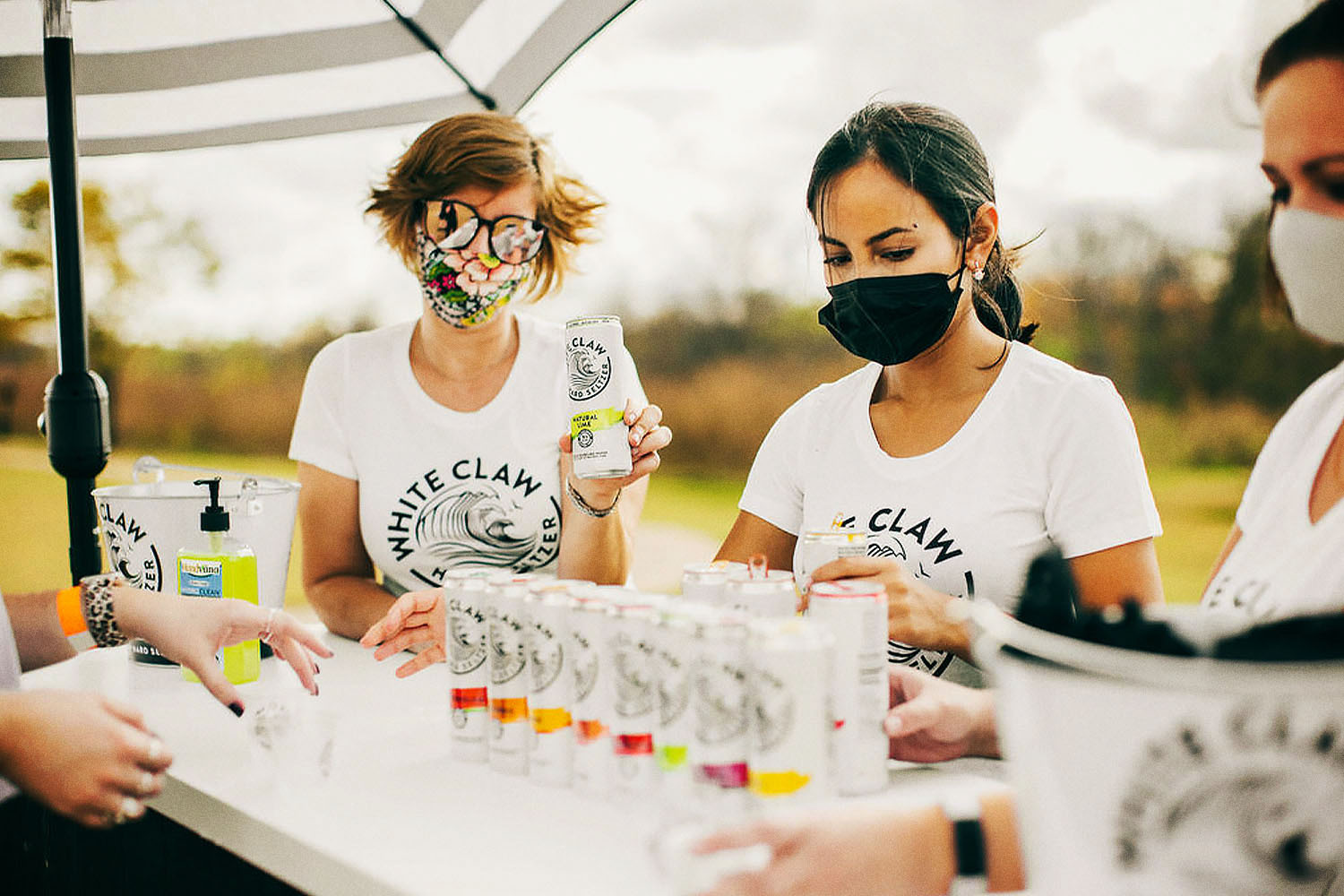 Three people serving White Claw at Seltzerland, a new traveling festival devoted to hard seltzers
