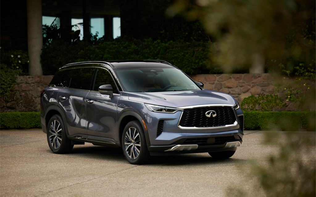 The all-new 2022 Infiniti QX60 luxury crossover sitting in a driveway next to a house with some greenery in the foreground