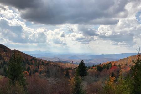 A view of a valley along the Appalachian Trail with white clouds in a blue sky and lots of trees with leaves changing colors