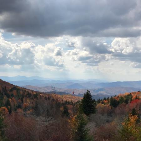 A view of a valley along the Appalachian Trail with white clouds in a blue sky and lots of trees with leaves changing colors