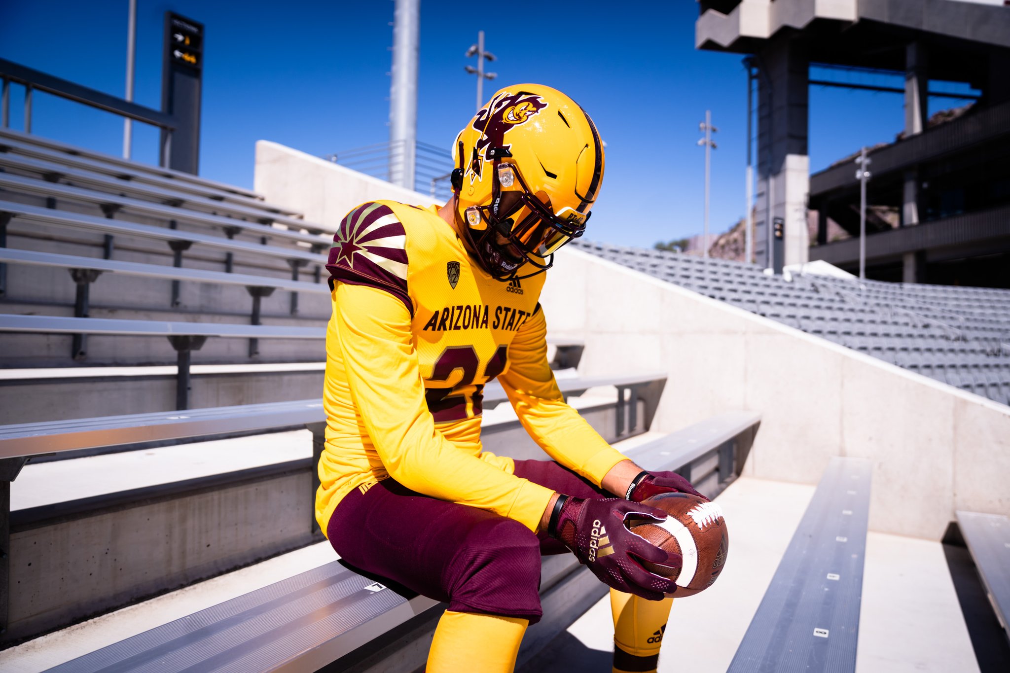 an arizona state football player wearing the team's new uniform for 2021 sits in the bleachers at sun devil football stadium in tempe, az