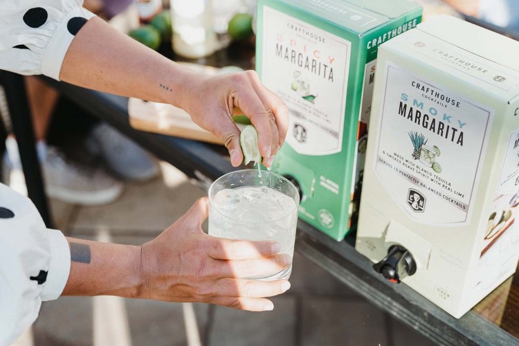 A person (off-camera) squeezing a lime over a margarita from Crafthouse Cocktails. The brand is one of several that's launched a "boxed cocktail" line, which makes it easier (and cheaper) to serve cocktails in a large-format setting