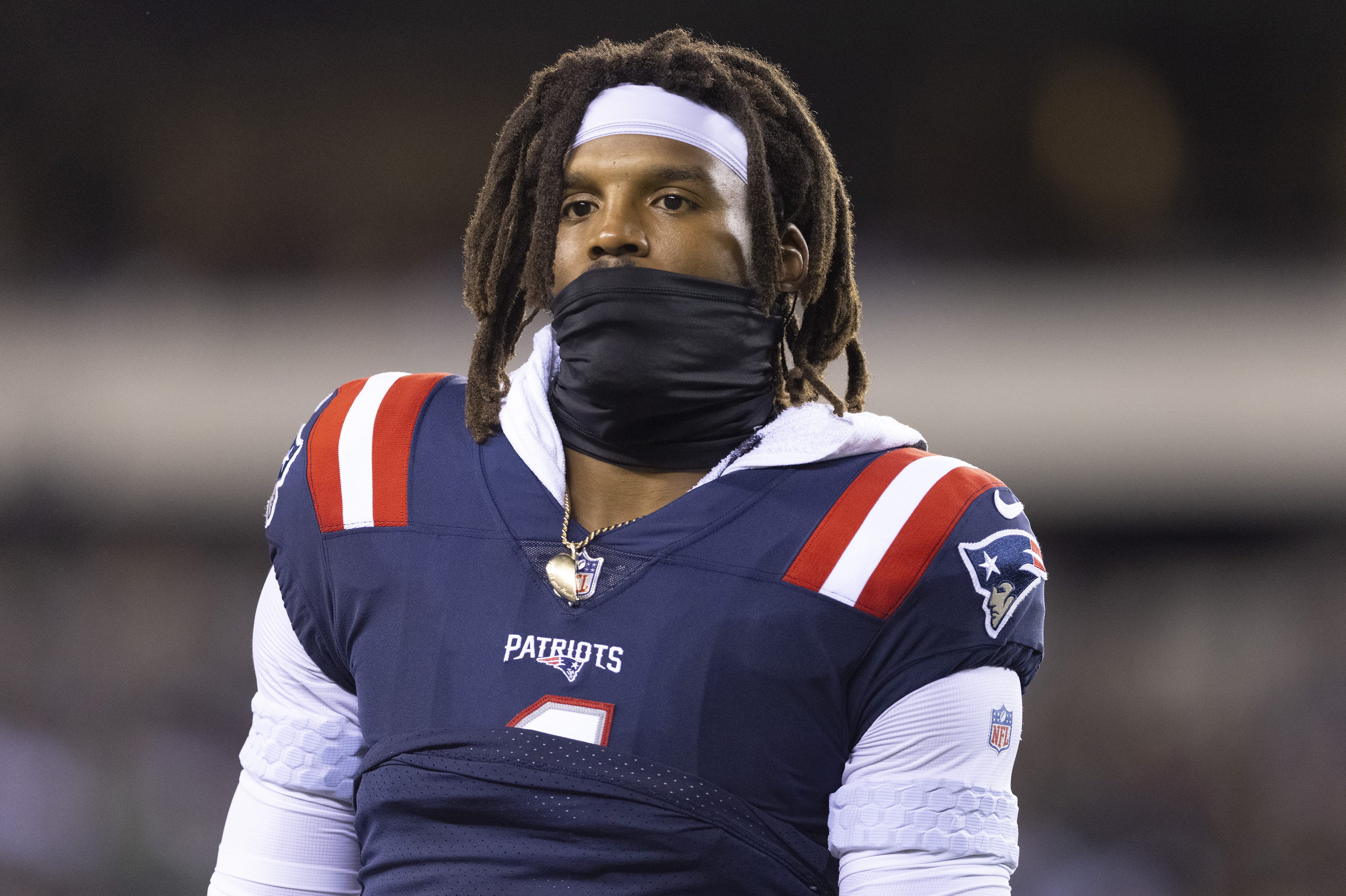 New England Patriots quarterback Cam Newton wearing a gaiter over his mouth and below his nose. The NFL player is at a competitive disadvantage because he is reportedly not vaccinated.