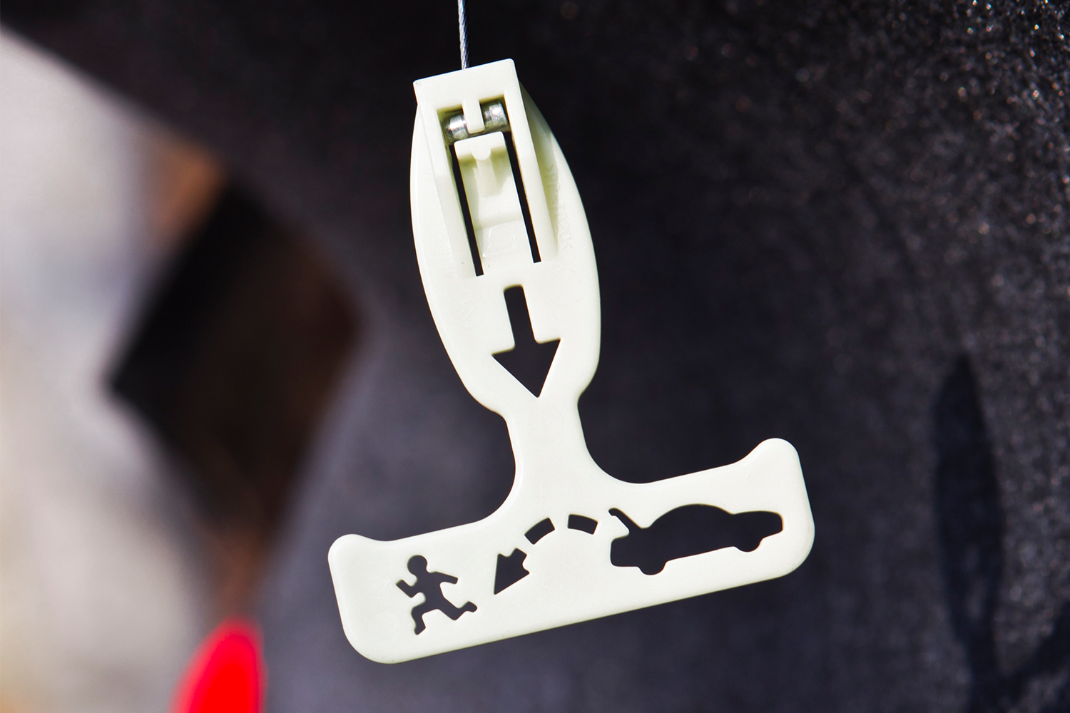 A glow-in-the-dark trunk release handle in the back of a car. After Janette Fennell was kidnapped, she advocated for the safety feature to be mandatory.