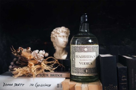 Harridan vodka on a table with various books and artwork — the vodka recently launched with a unique messaging (and real character)