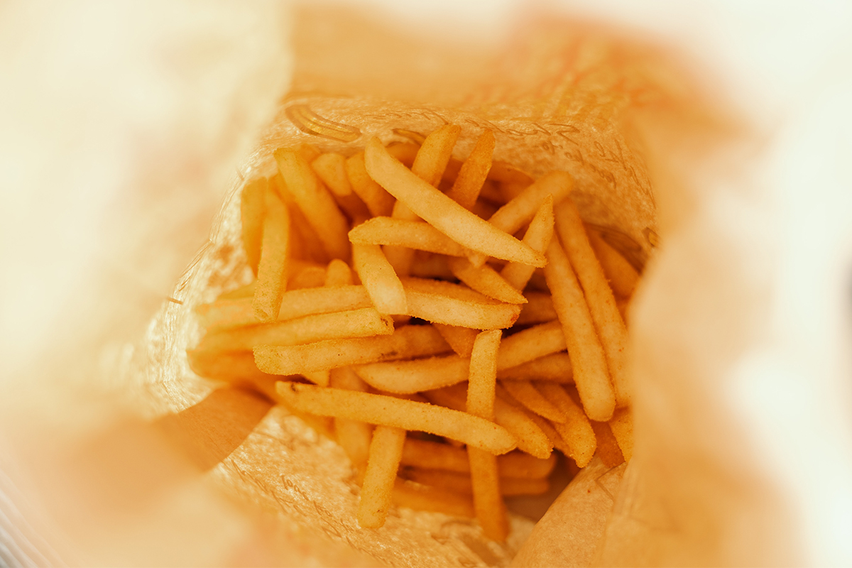 A photo of a a bunch of French fries at the bottom of a bag. Can fried food like this lead to migraines? A new study looks at the issue.