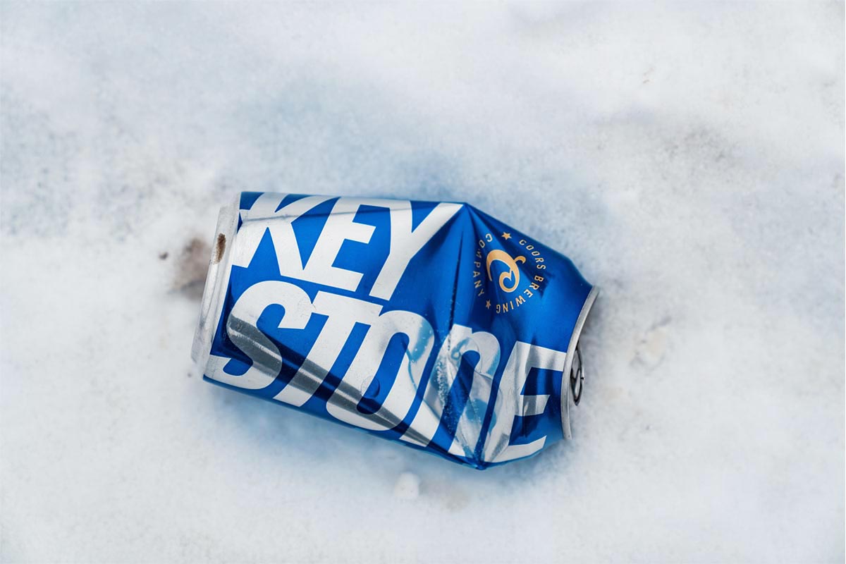 A crumpled aluminum can of Keystone beer near an ice fishing spot in Northern Minnesota in winter. Keystone is an alcoholic beverage made by the Molson Coors Brewing Company.