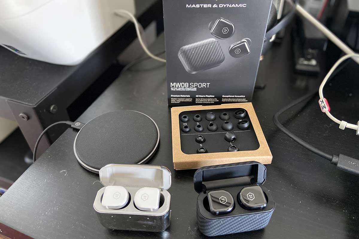 Comparing the old MW08 earbuds against the MW08 Sport (and shown with the wireless charging pad, foam and silicone tips and packaging