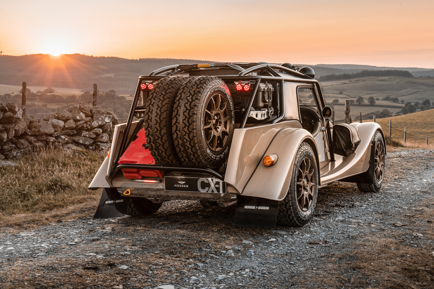 The rear end of the new Morgan Plus Four CX-T with an equipment rack holding extra wheels, tires and gas cans. The off-road sports car is available now.