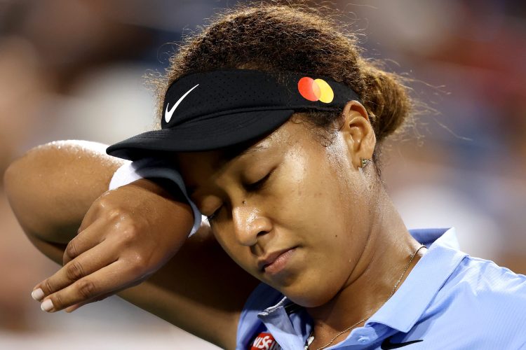 Tennis star Naomi Osaka of Japan wipes her face while playing. Her mental health struggles have led to the US Open enacting new procedures for the 2021 tournament.