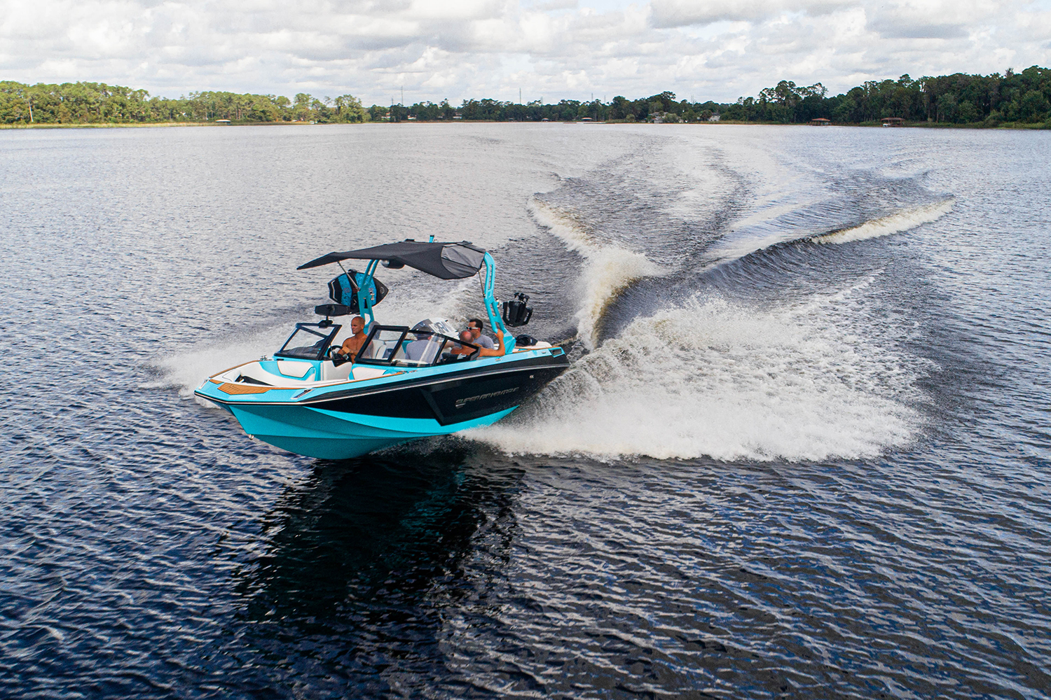 The Super Air Nautique GS22E electric wakesurfing and wakeboarding boat cruising on a lake. Correct Craft launched the all-electric towboat in 2020.