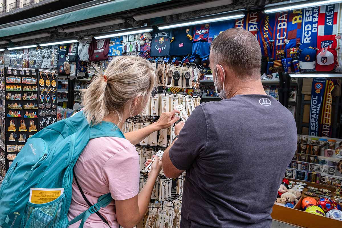Two tourists are seen buying souvenirs at one of the traditional newsstands on La Rambla. The economic balance of the economic sectors that depend on tourism closed in August below expectations due to the persistent mobility restrictions derived from the so-called fifth wave of Covid.