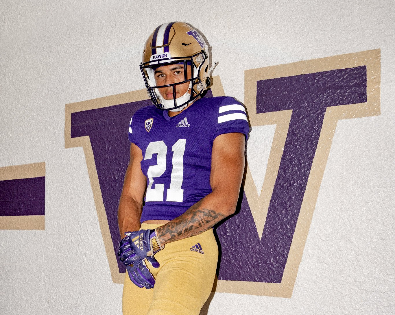 a university of washington football player in the purple and gold home uniform