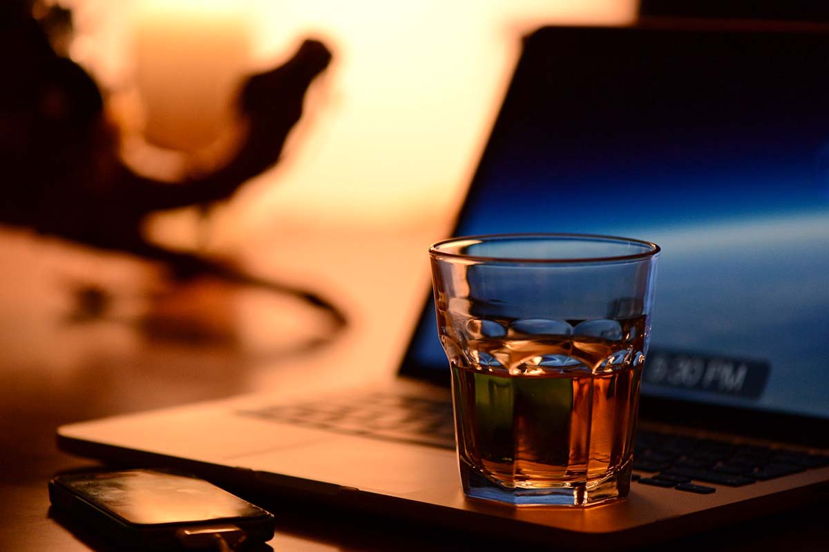 Whiskey, laptop and a smartphone on a desk. Whisky investment is entering the digital space.