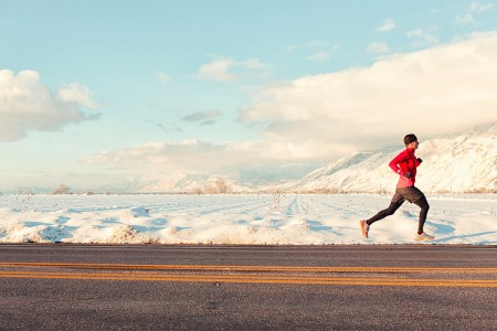 A man running past snowy mountains.
