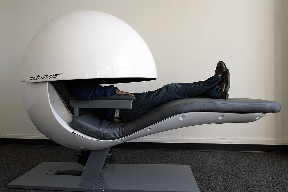 A man sleeps in a futuristic nap pod.