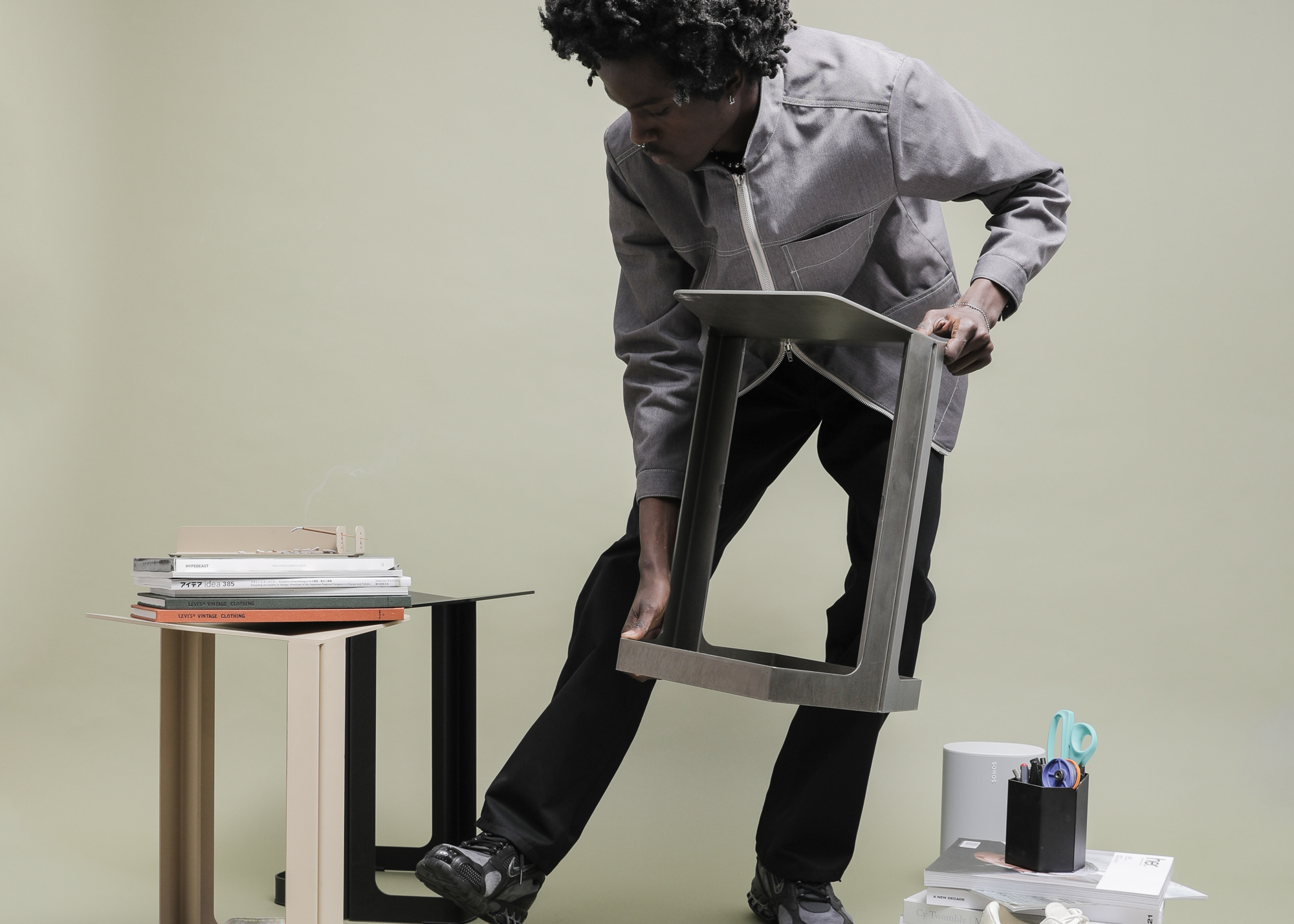 A man lifts up the new sheet metal stool from Oakland design company BASE