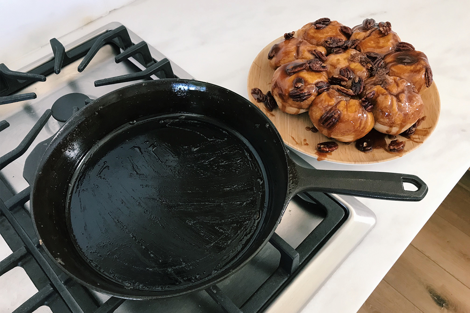 The No. 8 cast iron skillet from Field Company sitting on a stovetop next to a plate of pecan sticky buns on a white countertip