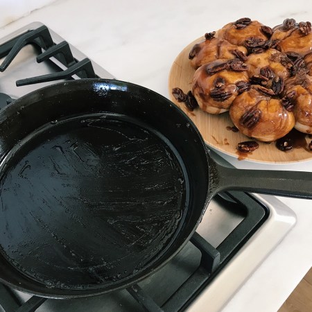 The Field Company No. 8 cast iron skillet sitting on a stovetop next to a plate of pecan sticky buns on a white countertop