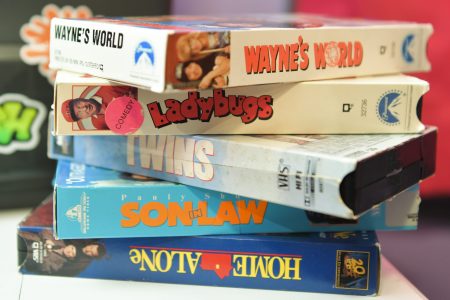A stack of retro VHS tapes including Wayne's World, Ladybugs, Twins, Son in Law and Home Alone