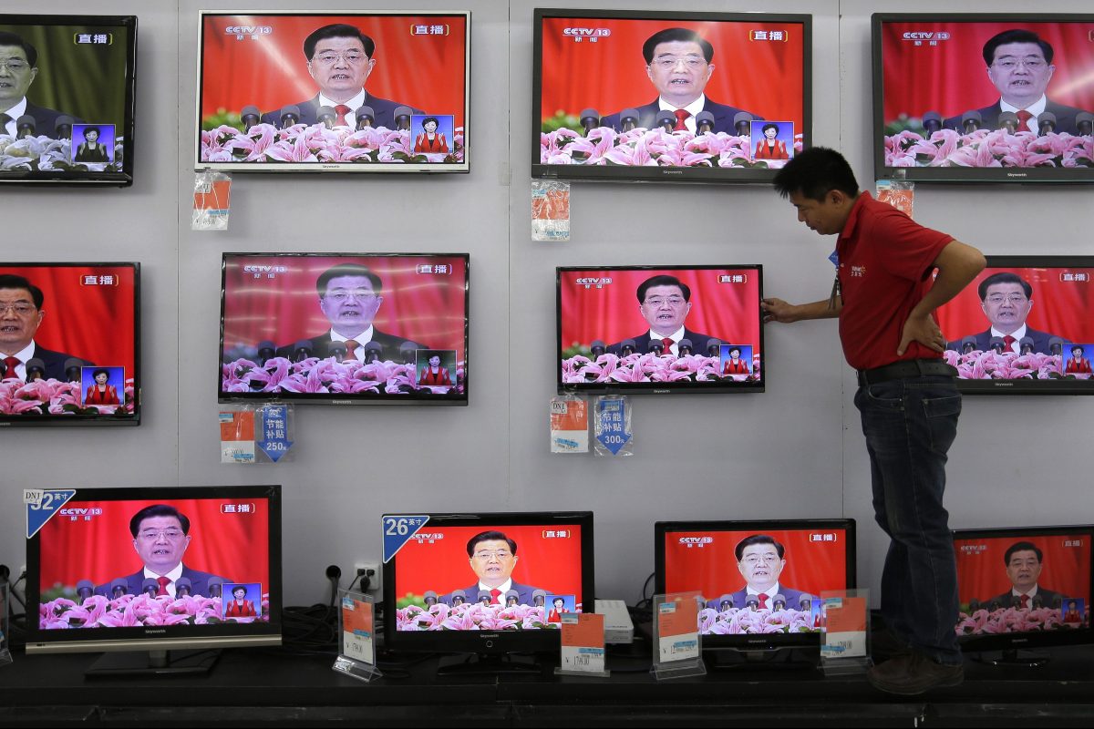 A man adjusts a television screen showing a live broadcast of former Chinese president Hu Jintao speaking at the opening of the 18th Communist Party Congress, at a supermarket in Wuhan, central China's Hubei province on 8 November 2012.