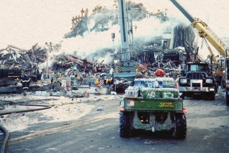 A green John Deere Gator utility vehicle loaded with packs of bottled water facing Ground Zero in the aftermath of the 9/11 terror attacks in New York City, the collapsed towers still on fire and smoking