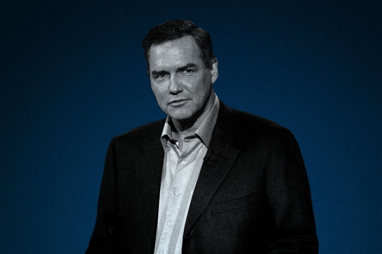 Comedian Norm MacDonald in a blazer and button-up shirt. MacDonald passed away this week at 61.
