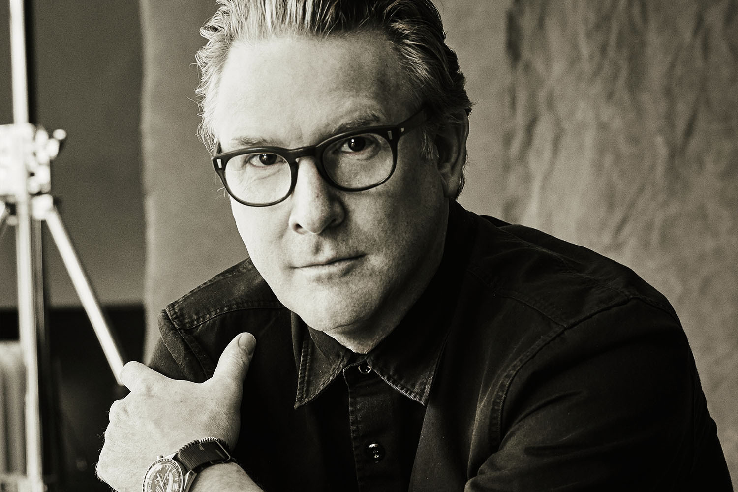 A portrait of menswear designer Todd Snyder, wearing glasses, a watch and a button-up shirt, on the occasion of the 10-year anniversary of his eponymous brand