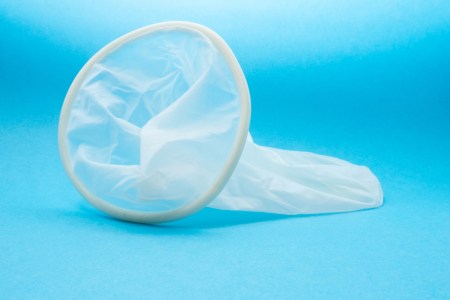 White condom rests against blue background. California is moving to outlaw "stealthing," or removing a condom during sex without consent.
