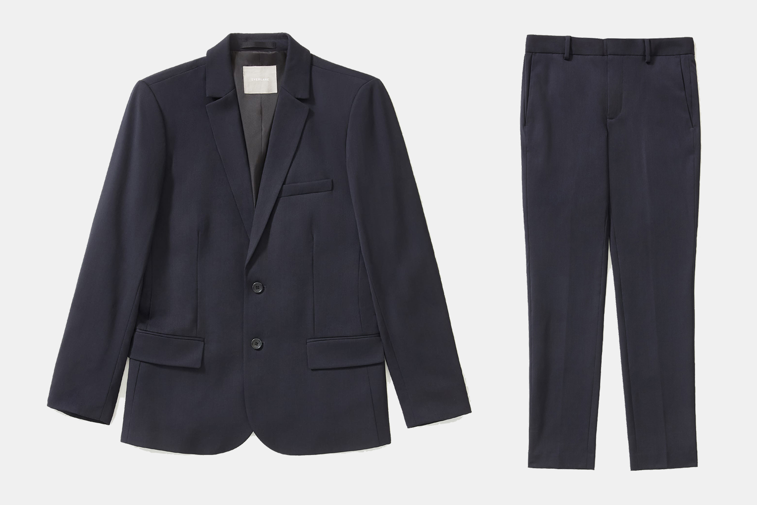 The men's Italian wool suit from Everlane on a grey background, including the suit jacket on the left and the trousers on the right