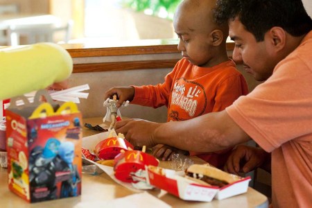 Five-year-old Andy Villatoro plays with a toy he received after ordering a Happy Meal at McDonald's as his father Carlos Villatoro (R) watches on November 3, 2010 in San Francisco, California. McDonald's is now switching away from plastic to more eco-friendly materials for toys in their Happy Meals.