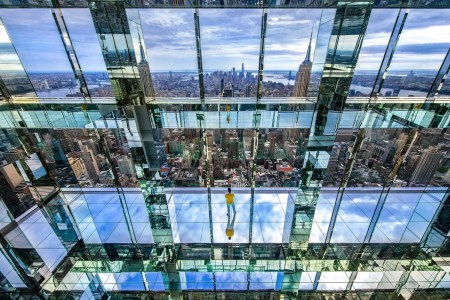 A man looking out onto the downtown Manhattan skyline at SUMMIT One Vanderbilt's mirror room.