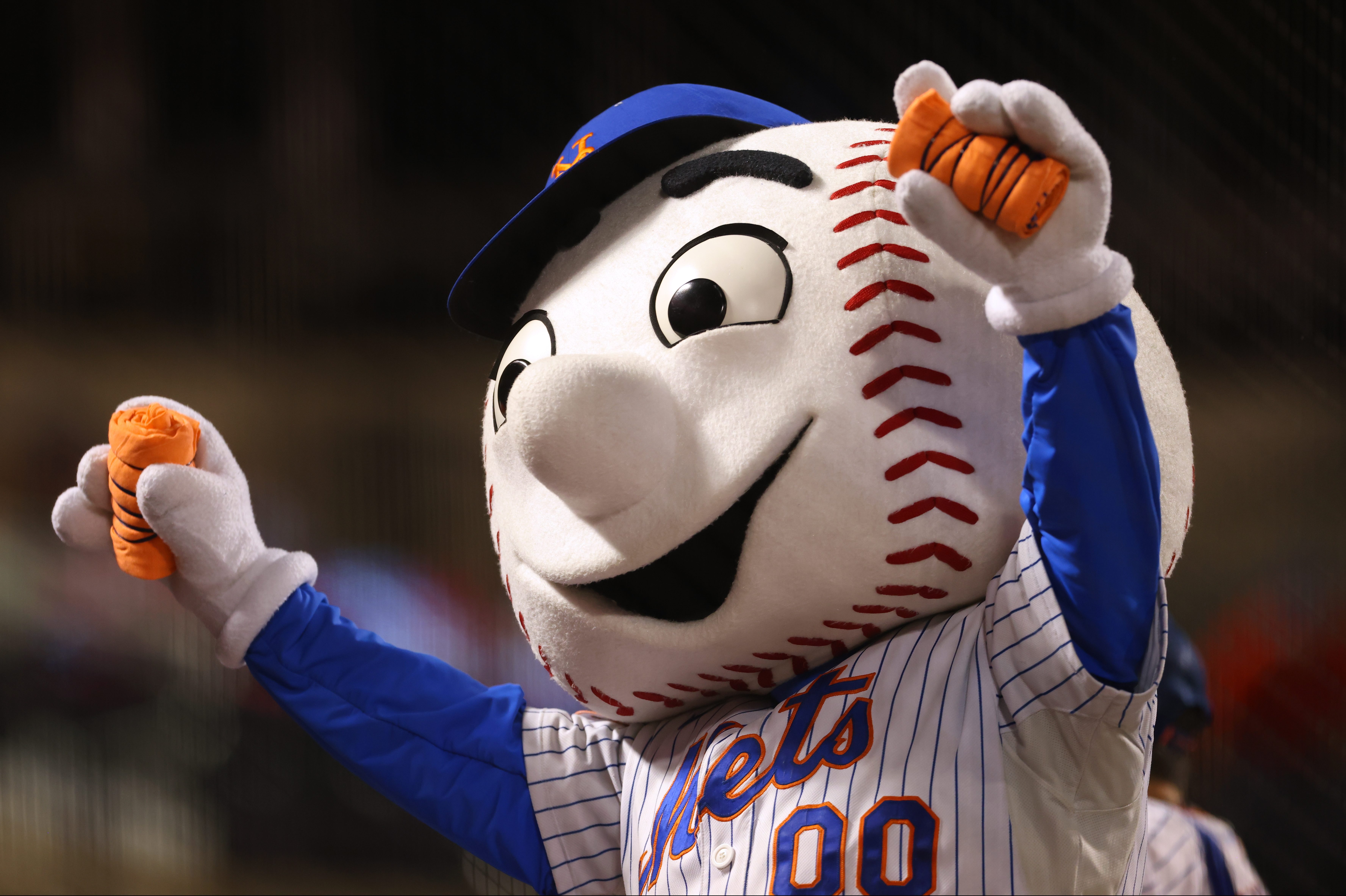 The mascot Mr. Met at a game between the Pirates and Mets at Citi Field with his hands up in the air
