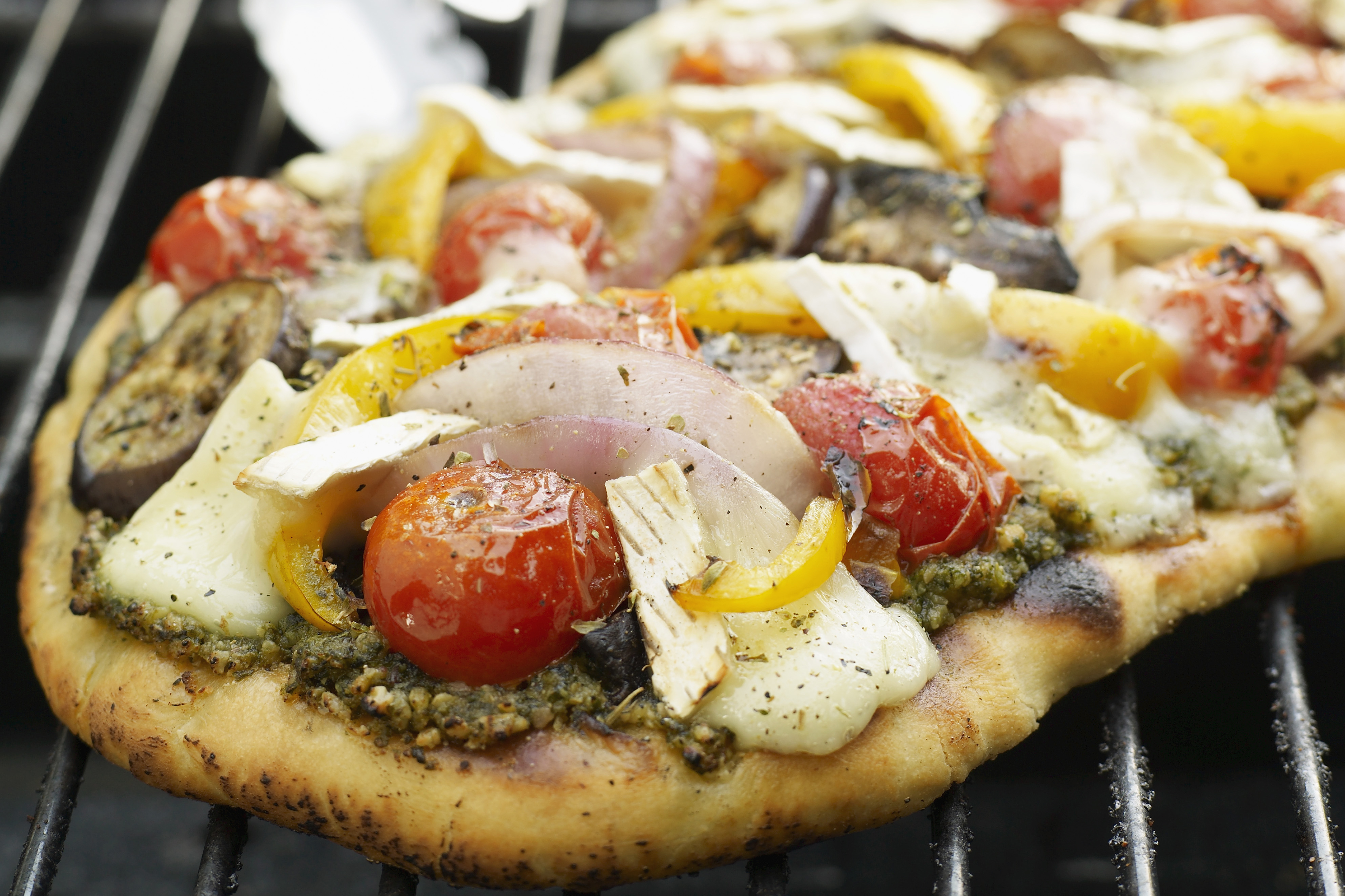 A pesto and vegetable pizza on the grill
