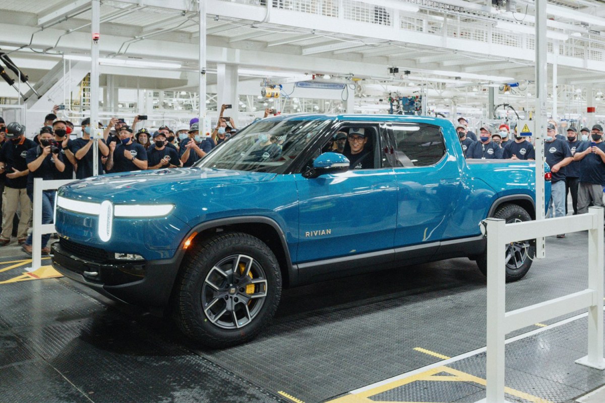 Rivian founder and CEO R.J. Scaringe sitting in a blue electric pickup truck, called the R1T, the first produced in the EV factory in September 2021
