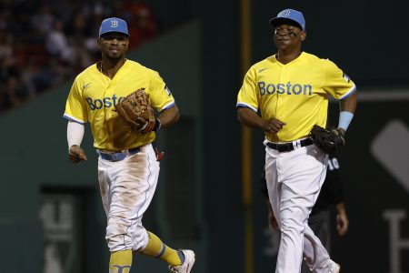 Rafael Devers and Xander Bogaerts of the Boston Red Sox share a laugh. The team is continuing to wear their yellow uniforms during a recent win streak.