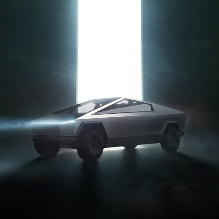 The Tesla electric Cybertruck from Elon Musk with its headlights on in front of a huge beam of light